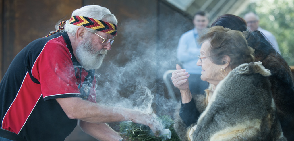 Elder conducting a Smoking Ceremony with community members